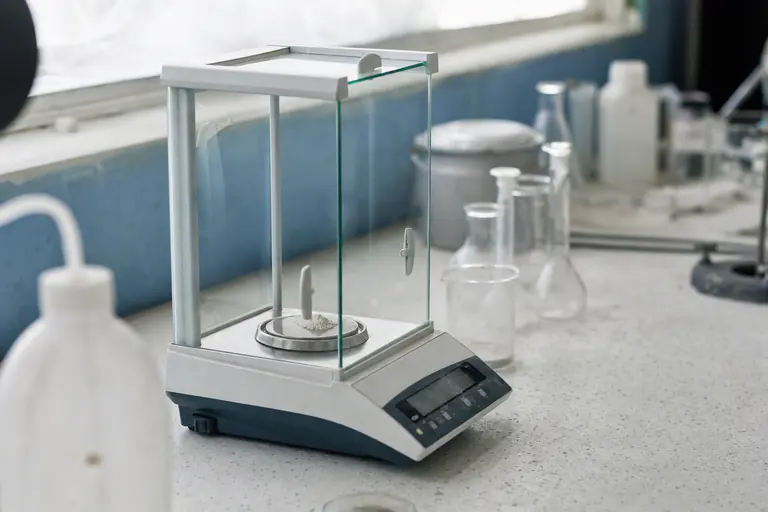 Analytische weegschaal met een spoor wit poeder op een laboratoriumtafel