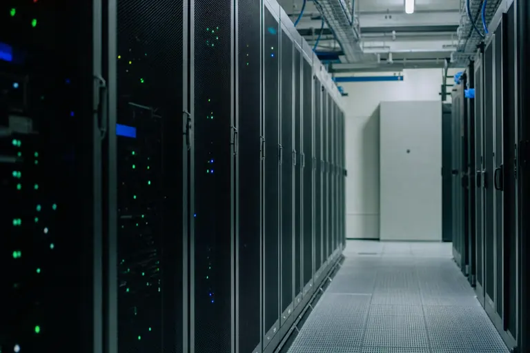 Gang in een serverruimte met rijen donkere apparatuurracks