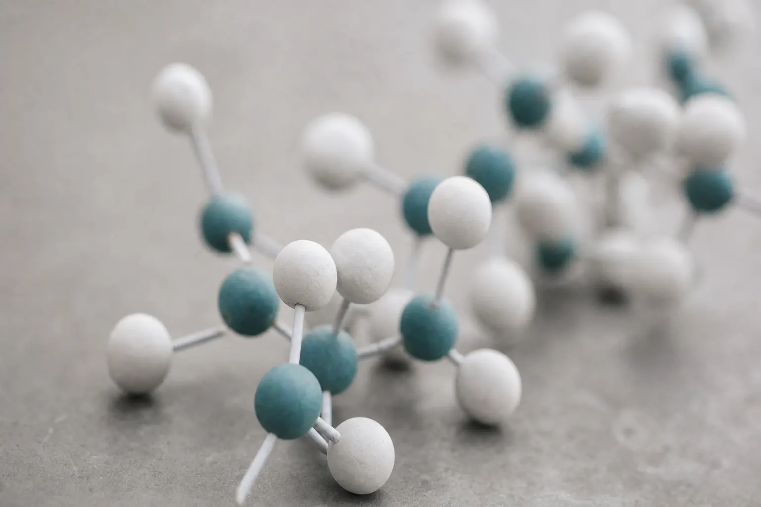 Moleculair balstokmodel van witte en teal gekleurde atomen op een grijs oppervlak